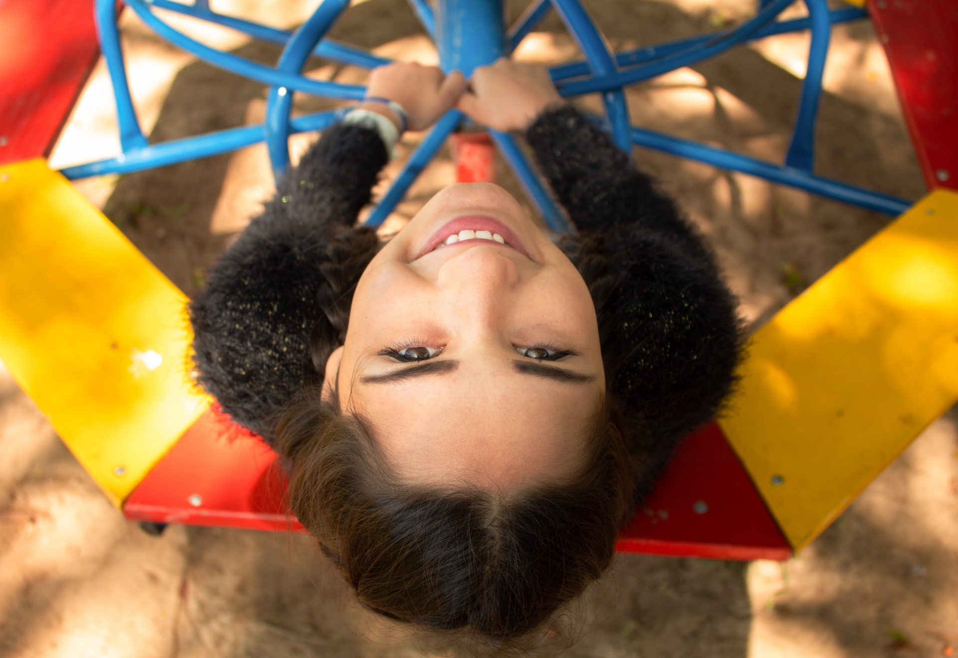 Child on playground equipment looking up and smiling