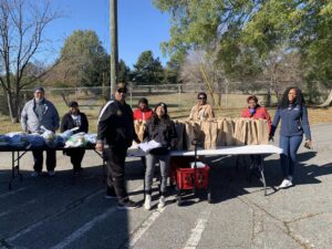 Volunteers of the New Hope Community Development group standing next to food and supplies for Greensboro community members