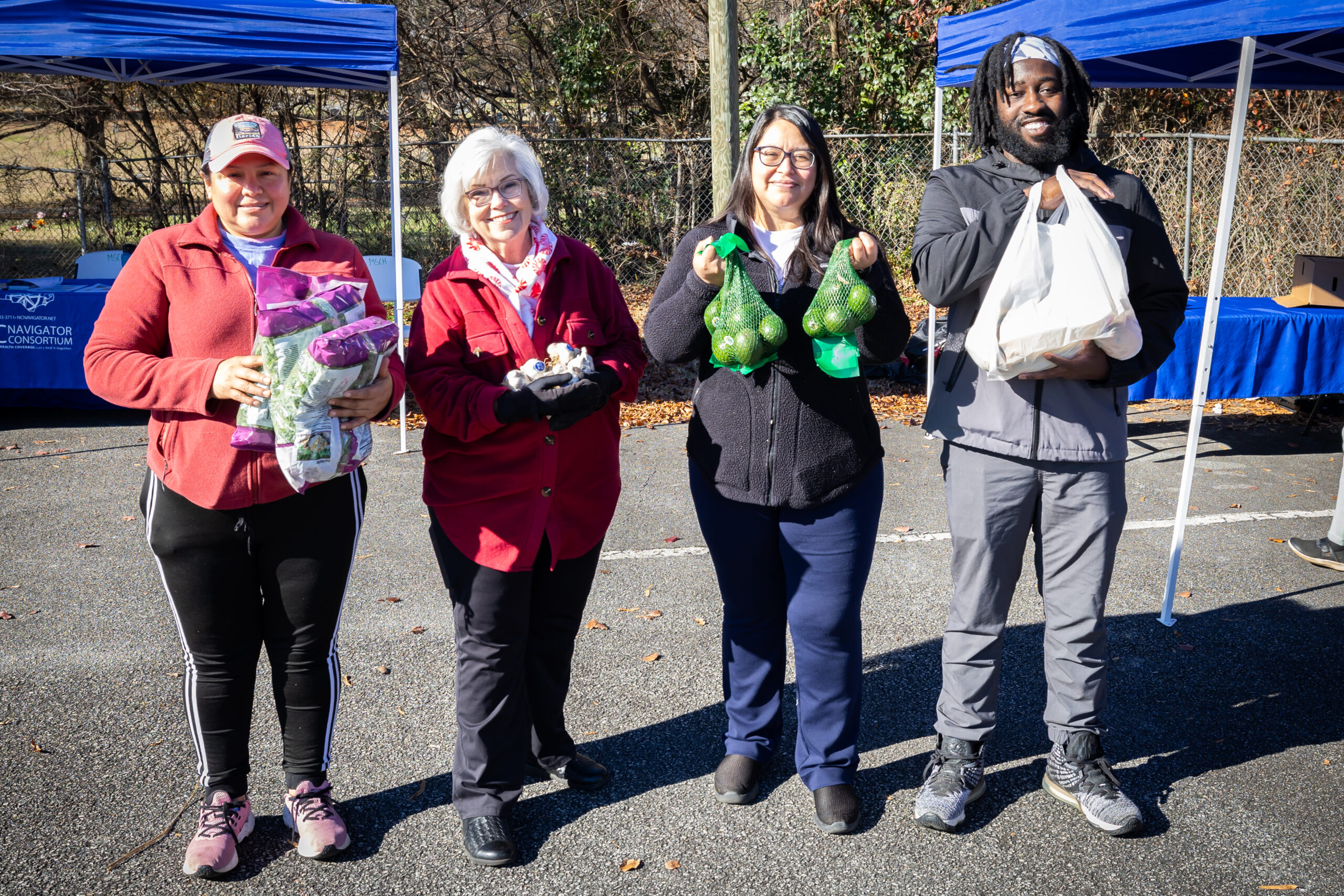 Four Greensboro community members holding food from cone health food drive
