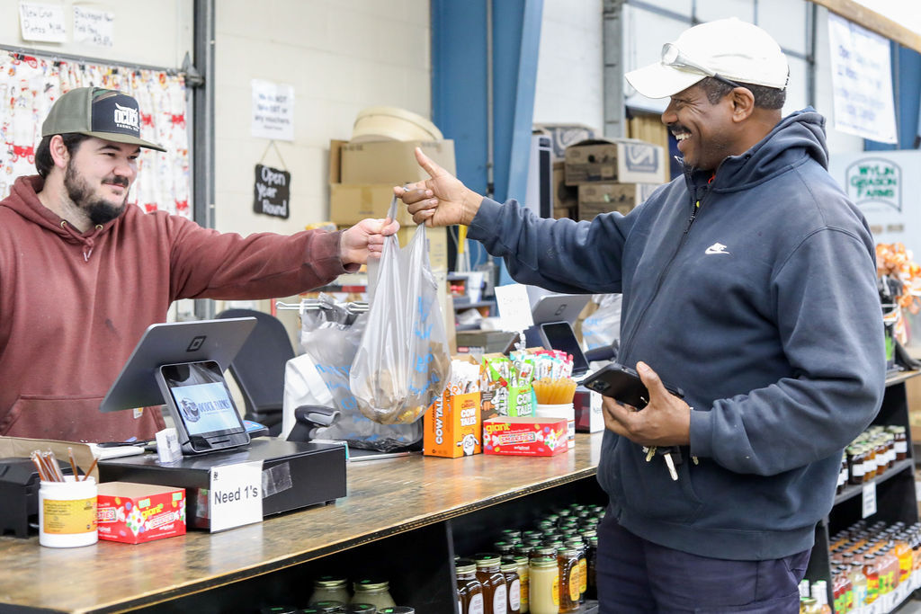 A cashier handing a plastic bag filled with food items to a man at the checkout counter